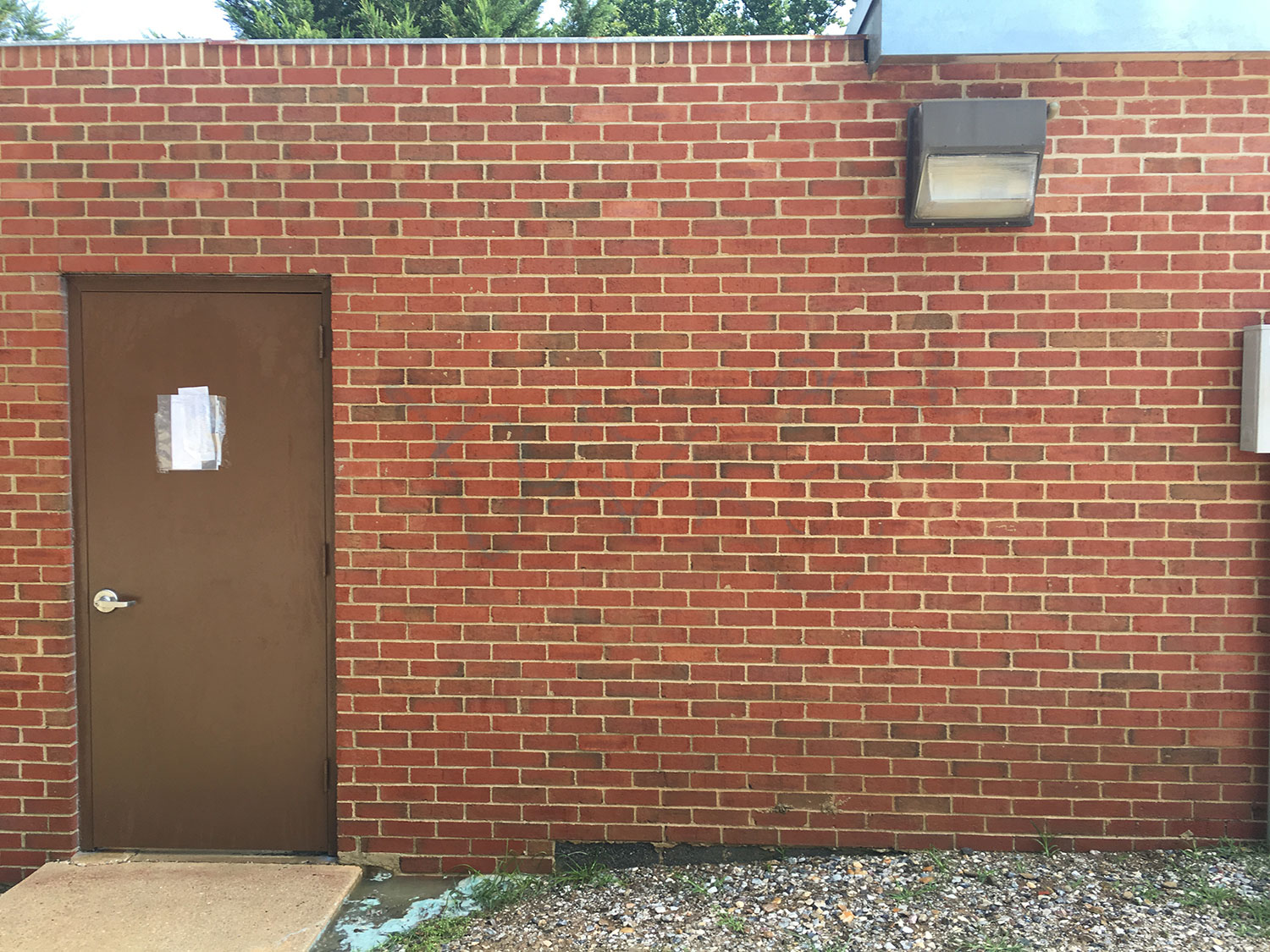 Brick commercial building with graffiti before professional pressure washing and graffiti removal to restore a clean exterior surface after.