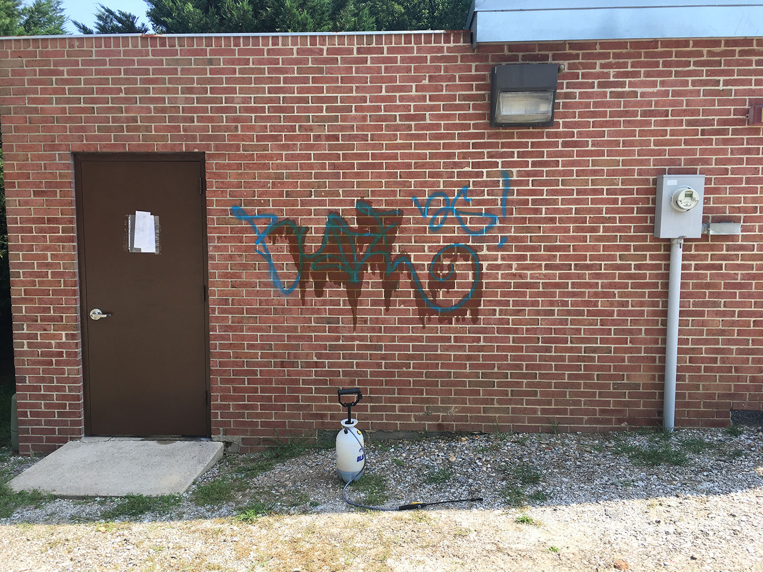 Brick commercial building with graffiti before professional pressure washing and graffiti removal to restore a clean exterior surface before.
