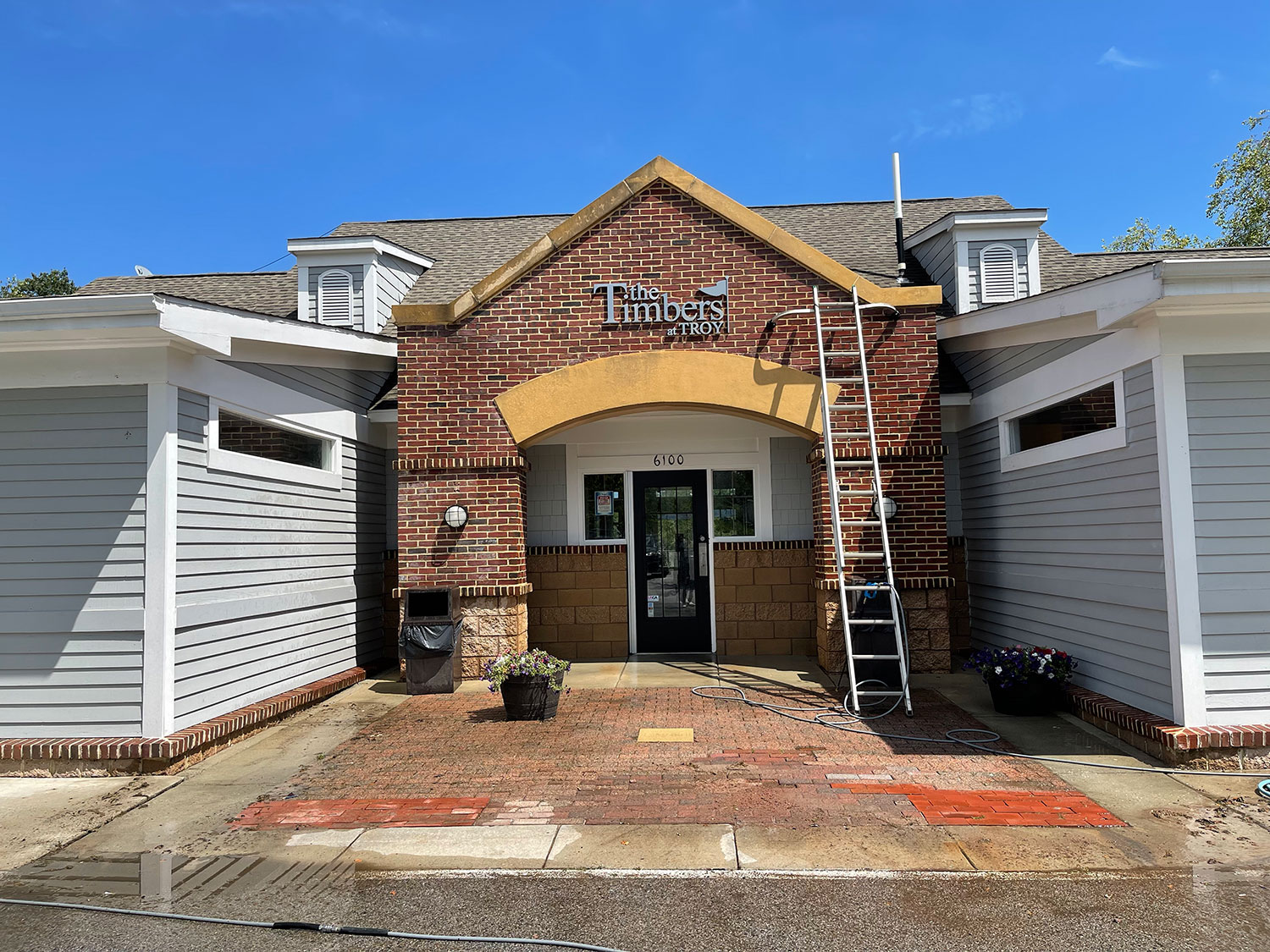Professional pressure washing equipment set up outside the entrance of a commercial building to clean brick, siding, and exterior surfaces.