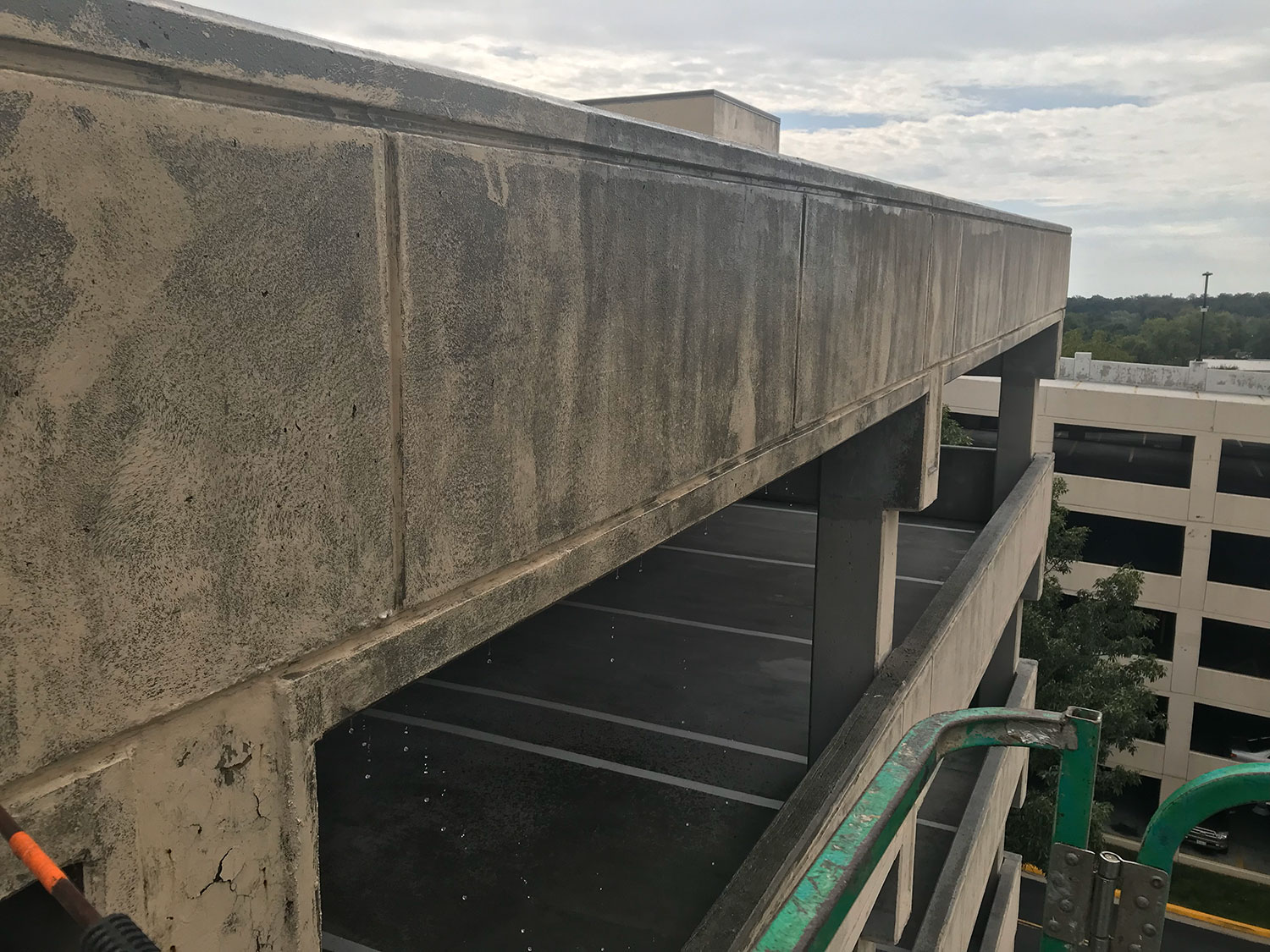 Concrete parking garage exterior with heavy dirt and streaking before professional pressure washing restores a clean, well-maintained appearance.