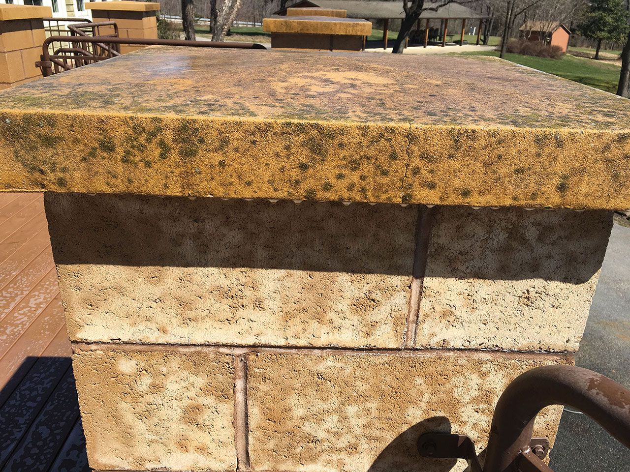 Stone column with visible algae, mildew, and weather staining before professional pressure washing restores its clean, natural appearance.