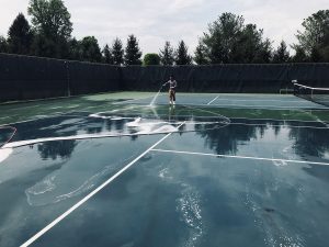 Professional pressure washing a tennis court to remove dirt, algae, and surface buildup, restoring a clean and safe playing surface.